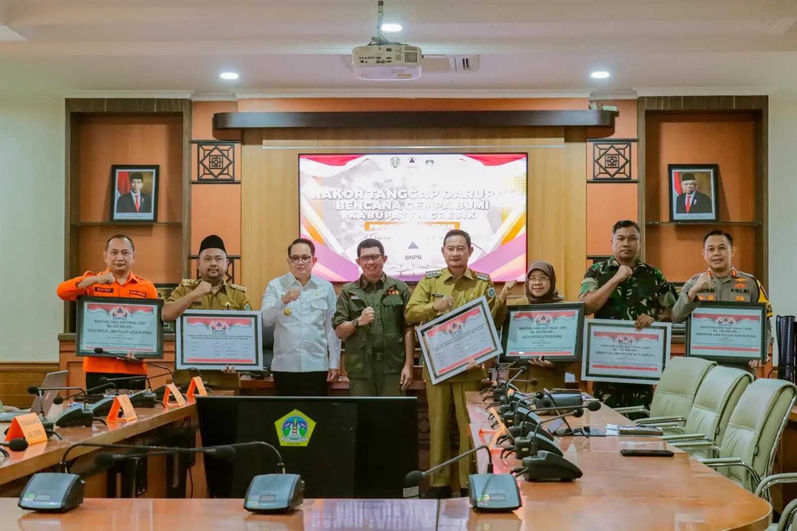 Kepala BNPB Letjen TNI Suharyanto, S.Sos., M.M (kemeja dan rompi hijau) saat memberikan simbolis dukungan bantuan penanganan darurat kepada pemerintah daerah, pada Rapat Koordinasi Penanganan Darurat Gempa di Kantor Bupati Gresik, Jawa Timur pada Senin (25/3).